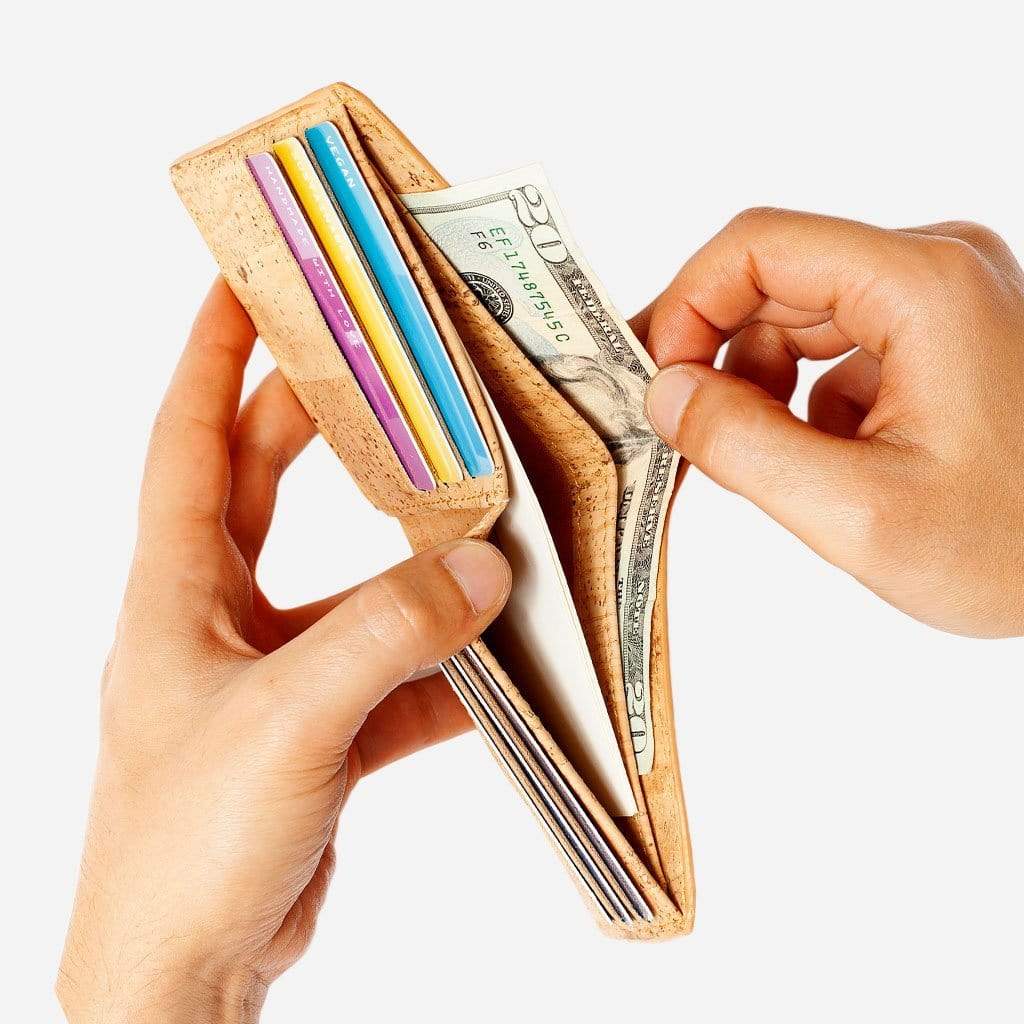 Hand taking out a 20 dollar bill from one of the bill compartments on the Bifold Wallet for Men. Light Brown Cork.